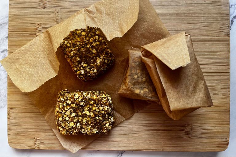 No-bake oaty squares with seeds and dates wrapped in brown baking paper