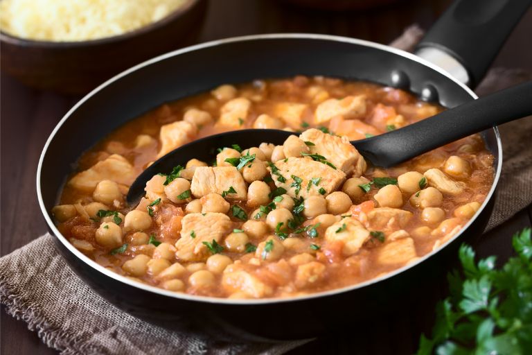 Chicken and chickpea stew in a pan with a serving spoon